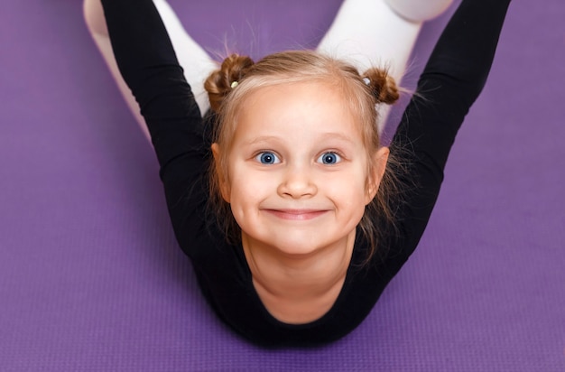 Foto lächelndes sportliches kind beim stretching portrait eines kleinen sportlers im training