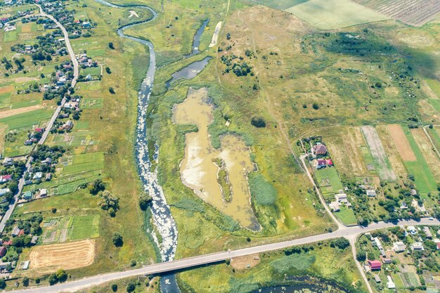 Ländliche Landschaft des Sommers. Luftaufnahme. Blick auf Dorf, Fluss, grüne Felder und Straße