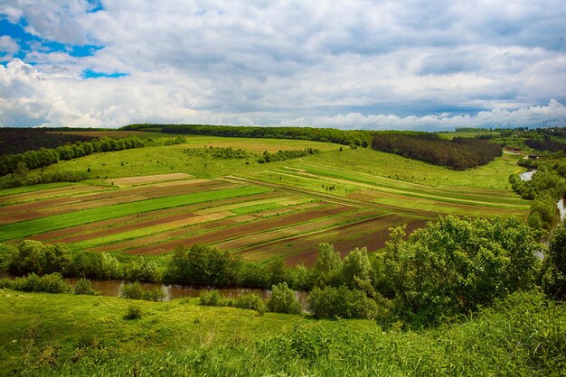 Ländliche Landschaft mit Feldwellen und blauem Himmel mit Wolkenfrühling saisonaler natürlicher Hintergrund