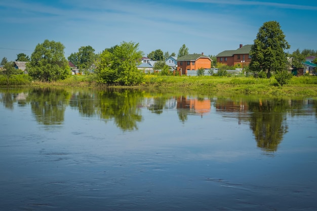 Ländliche Sommerlandschaft mit Fluss und blauem Himmel