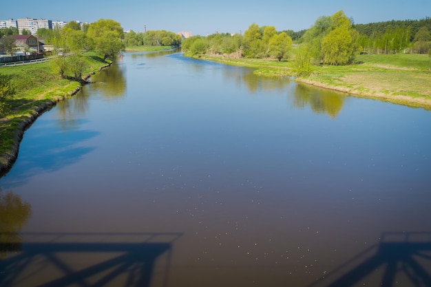 Ländliche Sommerlandschaft mit Fluss und blauem Himmel