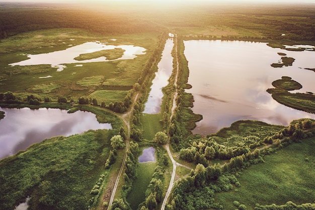 Ländliche Sommersonnenunterganglandschaft mit Sumpf der Flussseen und natürlichem Hintergrundluftbild des Sonnenscheins