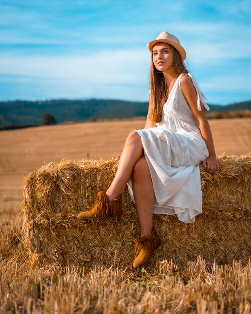 Ländlicher Lebensstil, Porträt eines jungen kaukasischen blonden Bauern im weißen Kleid und im weißen Hut im Sommer