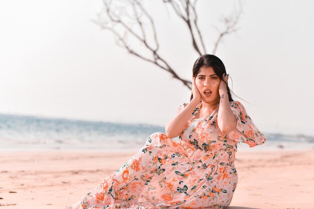 Lässige hübsche Mädchen-Frontpose, die am Strand indisch-pakistanisches Modell sitzt