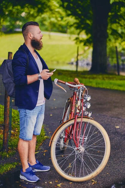 Lässiger bärtiger Mann in einem Park spricht per Smartphone.