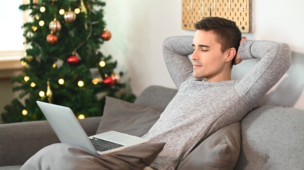 Lässiger Mann, der sich auf einem bequemen Sofa im Wohnzimmer entspannt.