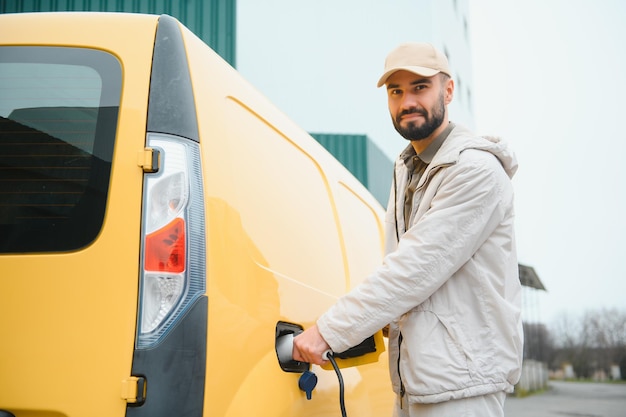 Lässiger Mann in der Nähe von Elektroautos, der auf das Ende des Batterieladevorgangs wartet