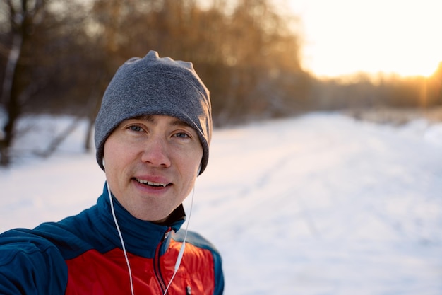 Läufer, die warme sportliche Kleidung in Kopfhörern tragen, machen Selfie