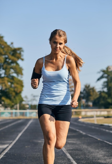 Läufer - Frau, die draußen Training für Marathonlauf läuft. Schönes Fitnessmodel in ihren 20ern.