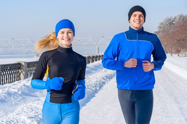 Läufer. Junge rennende Paare. Sportmann u. -Frau, die auf Winterdamm rütteln