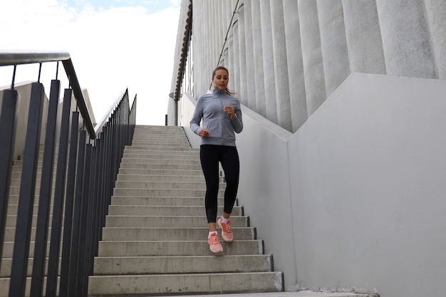 Läuferathlet, der auf Treppen läuft. Frauenfitness joggt im Freien.