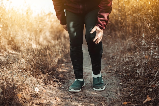 Läuferfrau mit Sportlaufknieverletzung. Hände, die Knie mit Schmerz halten Fitness-gesundes Lifestyle-Konzept.