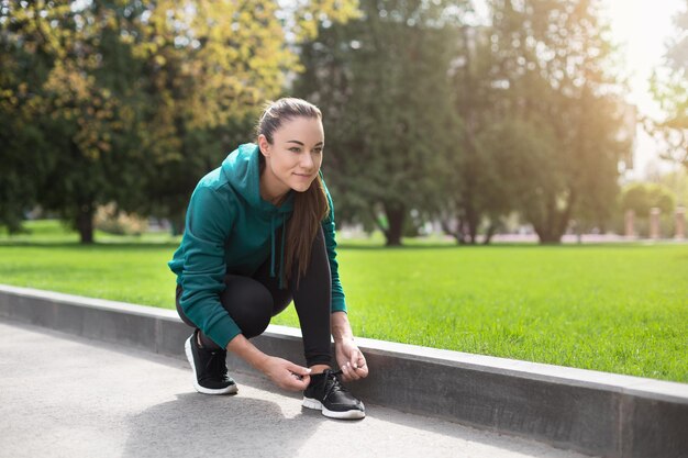 Läuferin, die ihre Laufschuhe beim morgendlichen Cardio-Training im Stadtpark bindet