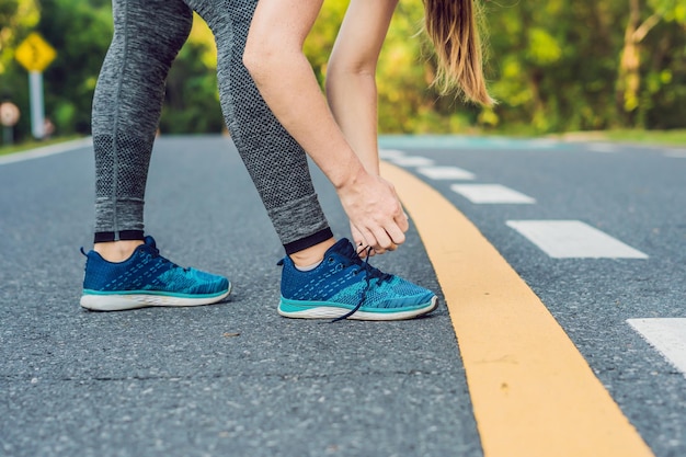 Läuferin, die ihre Schuhe bindet, die für das Joggen draußen vorbereitet. Junge girld Läufer, die für das Training fertig werden. Sportlicher Lebensstil