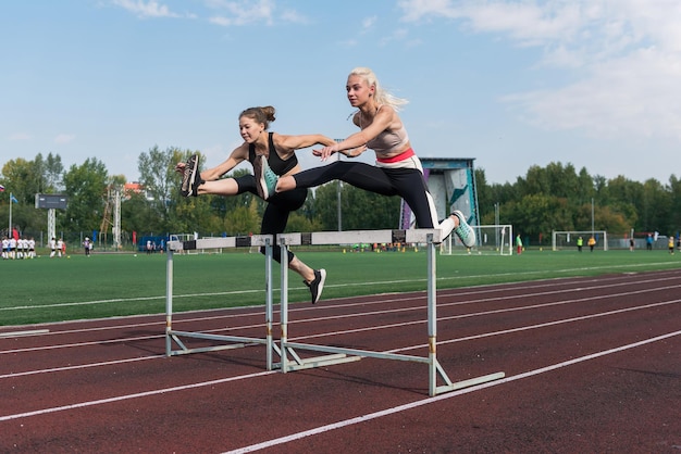 Läuferin mit zwei Athleten, die im Freien Hürden im Stadion laufen