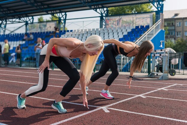 Läuferin mit zwei Athleten junge Frau am Start im Stadion im Freien