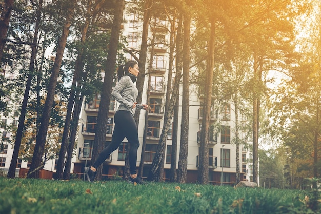 Läufertraining der jungen Frau im Herbststadtpark Gesundes Trainieren im Freien