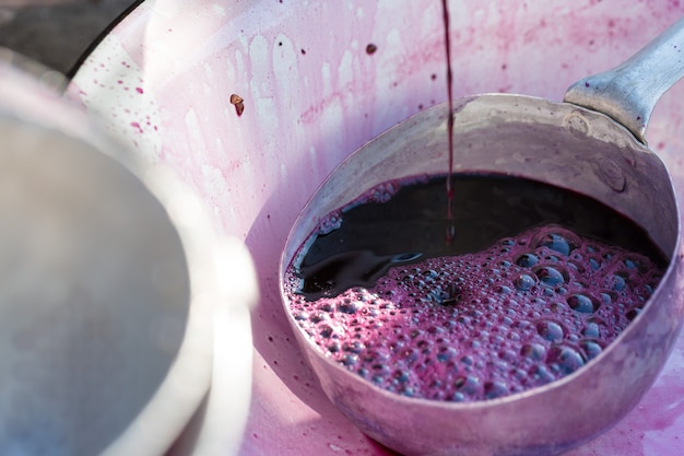 Lagar com mosto tinto e parafuso helicoidal. as mãos do enólogo fecham.