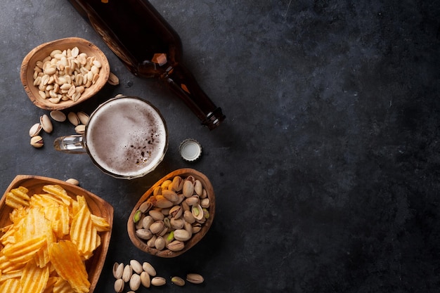 Lager de cerveza y aperitivos en mesa de piedra.