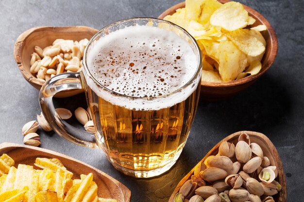 Lager de cerveza y aperitivos en mesa de piedra.