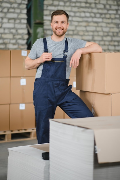 Lagerarbeiter, der einen Karton für die Lieferung an das Produktionslager trägt