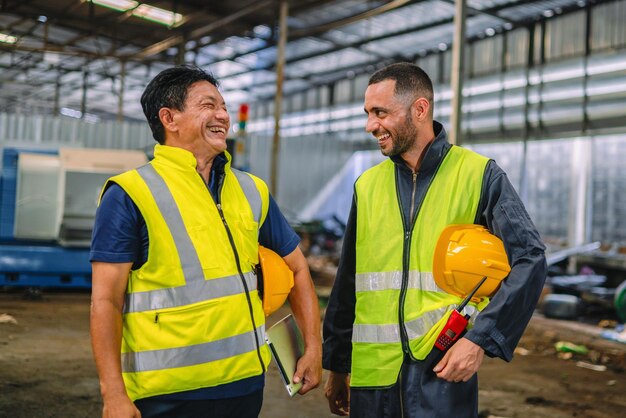 Lagerarbeiter in gelben Schutzhelmen, die lächeln und die Sicherheit gewährleisten, sind ein Beispiel für eine lebendige Industrieatmosphäre