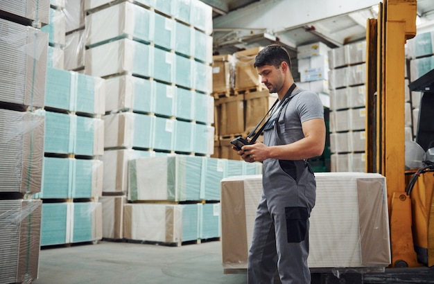 Lagerarbeiter in Uniform und Tablet in Händen kontrolliert die Produktion.