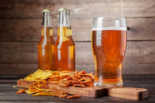 Lagerbier und Imbisse auf Holztisch. Nüsse, Pommes, Brezel