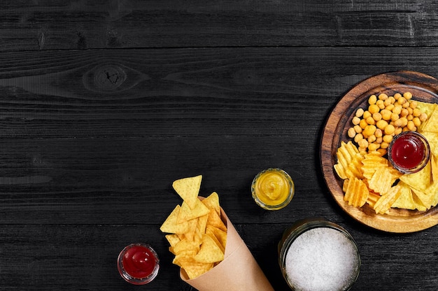 Lagerbier und Snacks auf schwarzen Holznüssen Chips Draufsicht mit Exemplar