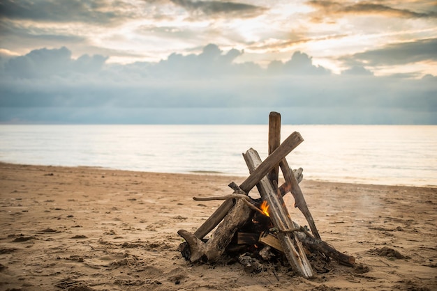 Lagerfeuer am Strand mit dramatischen Wolken