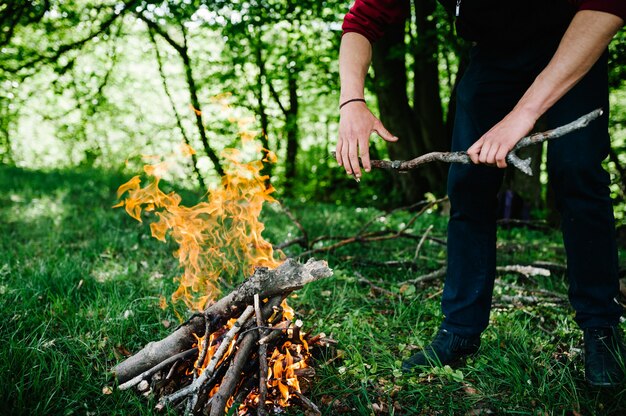 Lagerfeuer in der Natur. Der Zweig ist in den Händen des Menschen