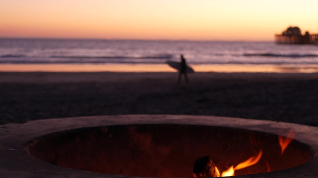 Lagerfeuerstelle, Kalifornien USA. Lagerfeuer brennt am Ozeanstrand, Lagerfeuerflamme im Zementring. Surfer