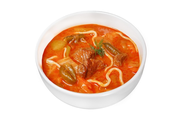 Lagman-Suppe auf einem tiefweißen Teller auf einem isolierten schwarzen Hintergrund