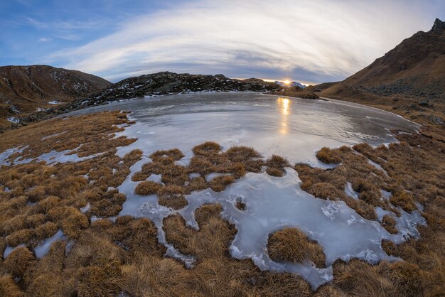 Lago alpino congelado de alta altitude, vista de olho de peixe ao pôr do sol