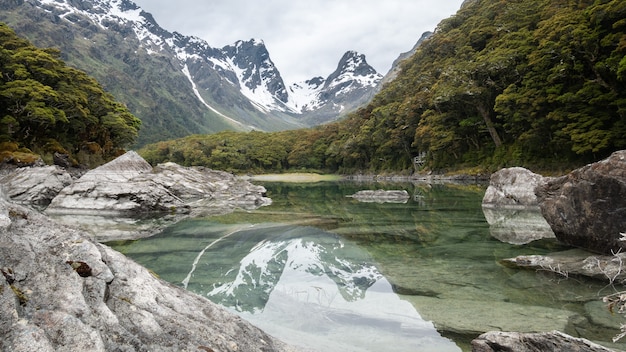 Lago alpino intocado refletindo o ambiente circundante, filmado na trilha de routeburn, na nova zelândia