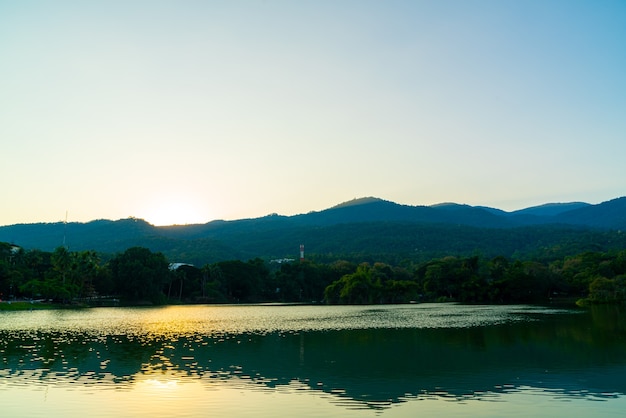 Lago Ang Kaew en la Universidad de Chiang Mai con montañas boscosas y cielo crepuscular