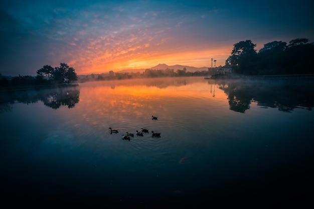 Un lago con un atardecer de fondo