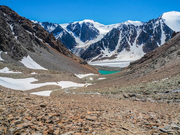 Lago azul da montanha na caldeira. Cordilheira contra um céu azul nublado. A caldeira de um vulcão extinto está rodeada por uma cordilheira. No vale há um lago azul com costões rochosos íngremes