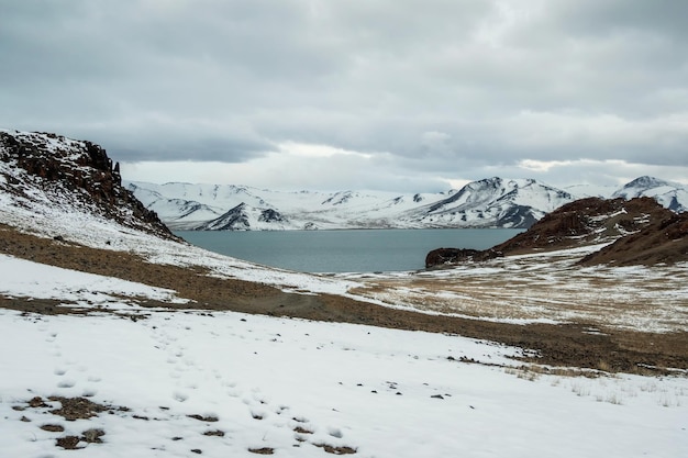 Foto lago azul de inverno e montanhas de neve a estrada de terra para o lago está coberta de neve