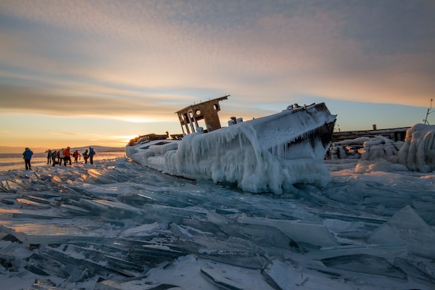 Lago Baikal al atardecer, todo está cubierto de hielo y nieve, un espeso hielo azul claro. Lago Baikal en los rayos del sol poniente. Lugar increíble, patrimonio mundial de la UNESCO.