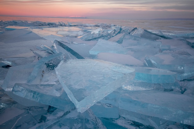 El lago Baikal al atardecer, todo está cubierto de hielo y nieve, espeso hielo azul claro.