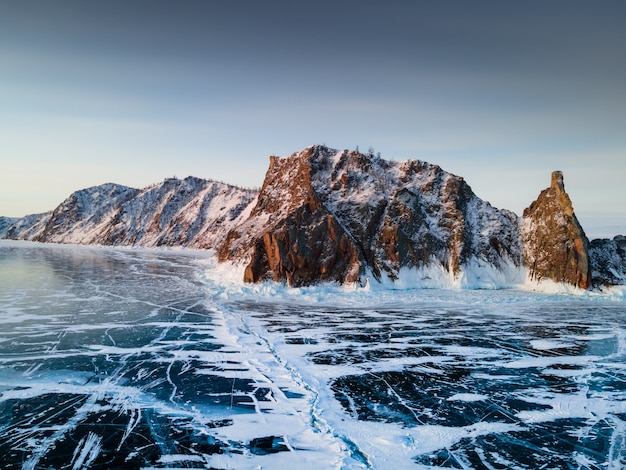 Lago Baikal en invierno con hielo azul transparente. Cabo Khoboy de la isla de Olkhon, Baikal, Siberia, Rusia. Vista aérea de drones. Hermoso paisaje de invierno al amanecer.