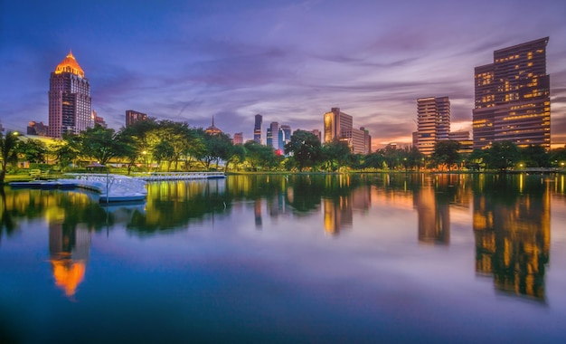 Lago calmo iluminado com edifícios refletidos contra o céu na cidade