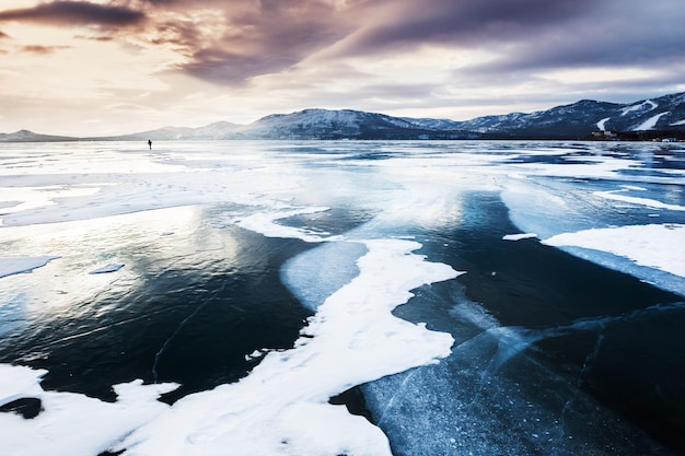 Lago congelado e montanhas ao pôr do sol. Linda paisagem de inverno