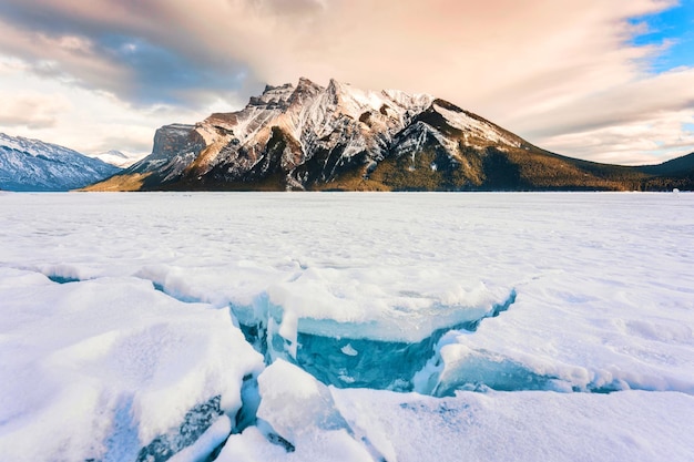 Lago congelado minnewanka com montanhas rochosas e gelo rachado do lago no inverno no parque nacional de banff