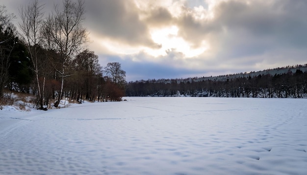 Un lago congelado en la nieve con el sol brillando a través de las nubes