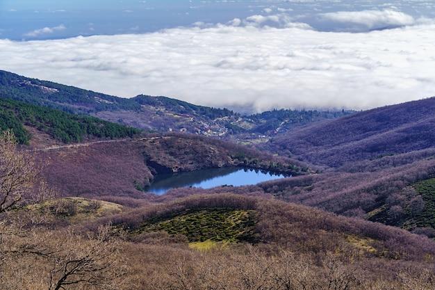 Lago de águas azuis no vale, entre montanhas verdes e nuvens abaixo da cidade que você pode ver. Miraflores Madrid.