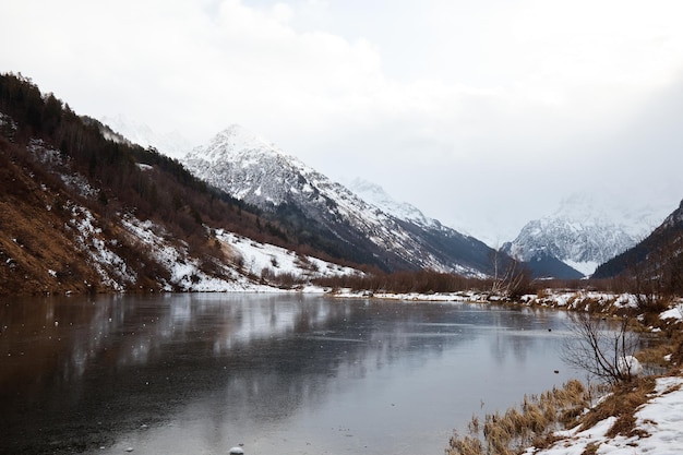 Lago de montanha de inverno na neve no fundo da lagoa de paisagem de montanha com gelo na água