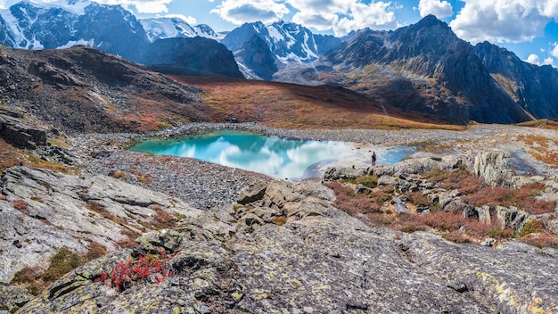 Lago de montanha limpo incrível em um vale de alta altitude. Bela natureza das montanhas de Altai. Lago no vale, rochas e neve. Maravilhoso dia ensolarado de verão com lindo cloudscape. Vista panorâmica.