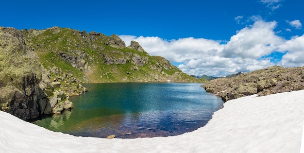 Lago de montanha pequena com neve até a borda